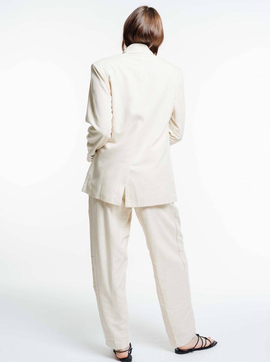 A woman in a cream suit with an Ecru Silk Noil Bea Blazer, displaying a menswear-inspired look.