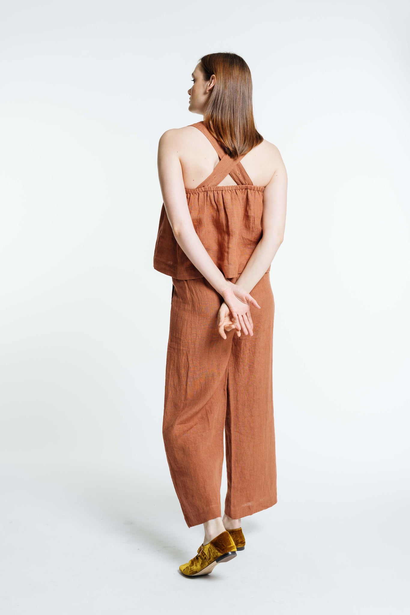 The back view of a woman wearing a Breeze Tank - Amber Brown jumpsuit.
