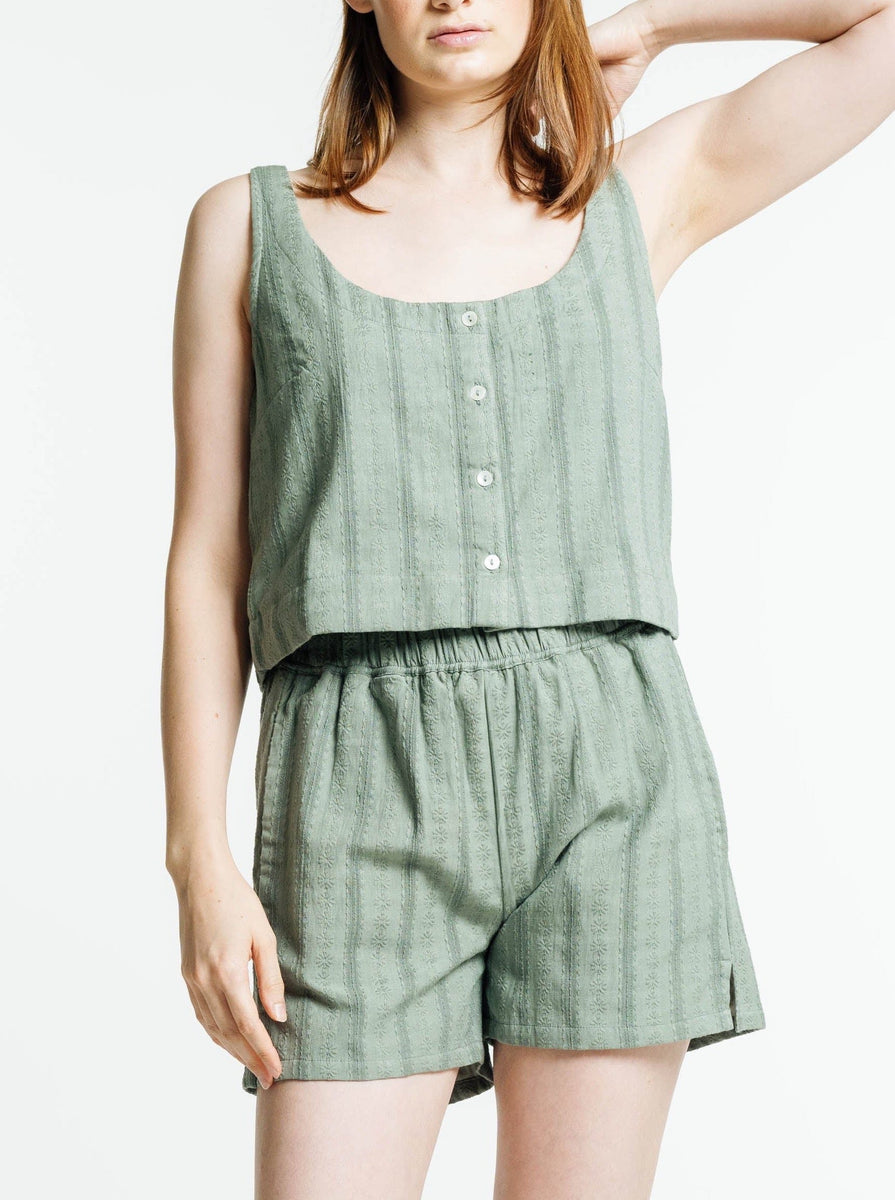 The model is donning a chic green Market Tank - Azure Broderie with shorts for a stylish and sun-kissed look.