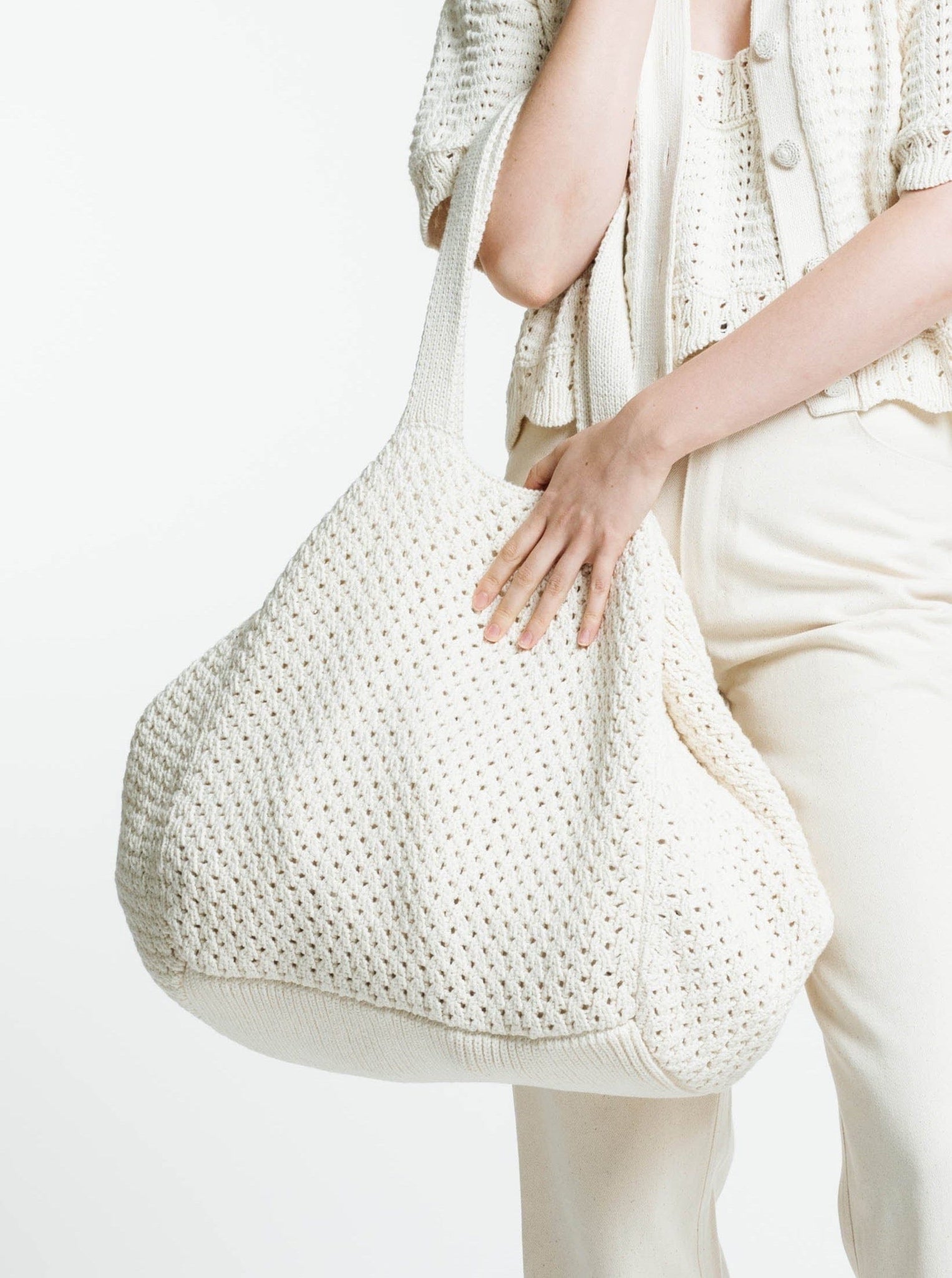 A person carrying a large white Crochet Slouchy Tote - Ivory bag, handmade in Peru.